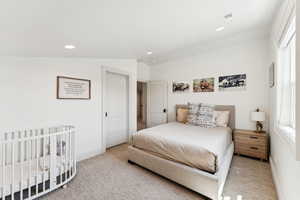 Bedroom featuring a nursery area, carpet flooring, and recessed lighting