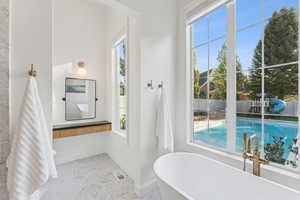 Full bath featuring a freestanding tub and light marble finish flooring
