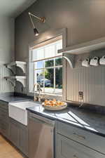 Kitchen with dark countertops, open shelves, gray cabinets, and stainless steel dishwasher
