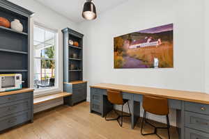 Office space featuring built in study area and light wood-style floors