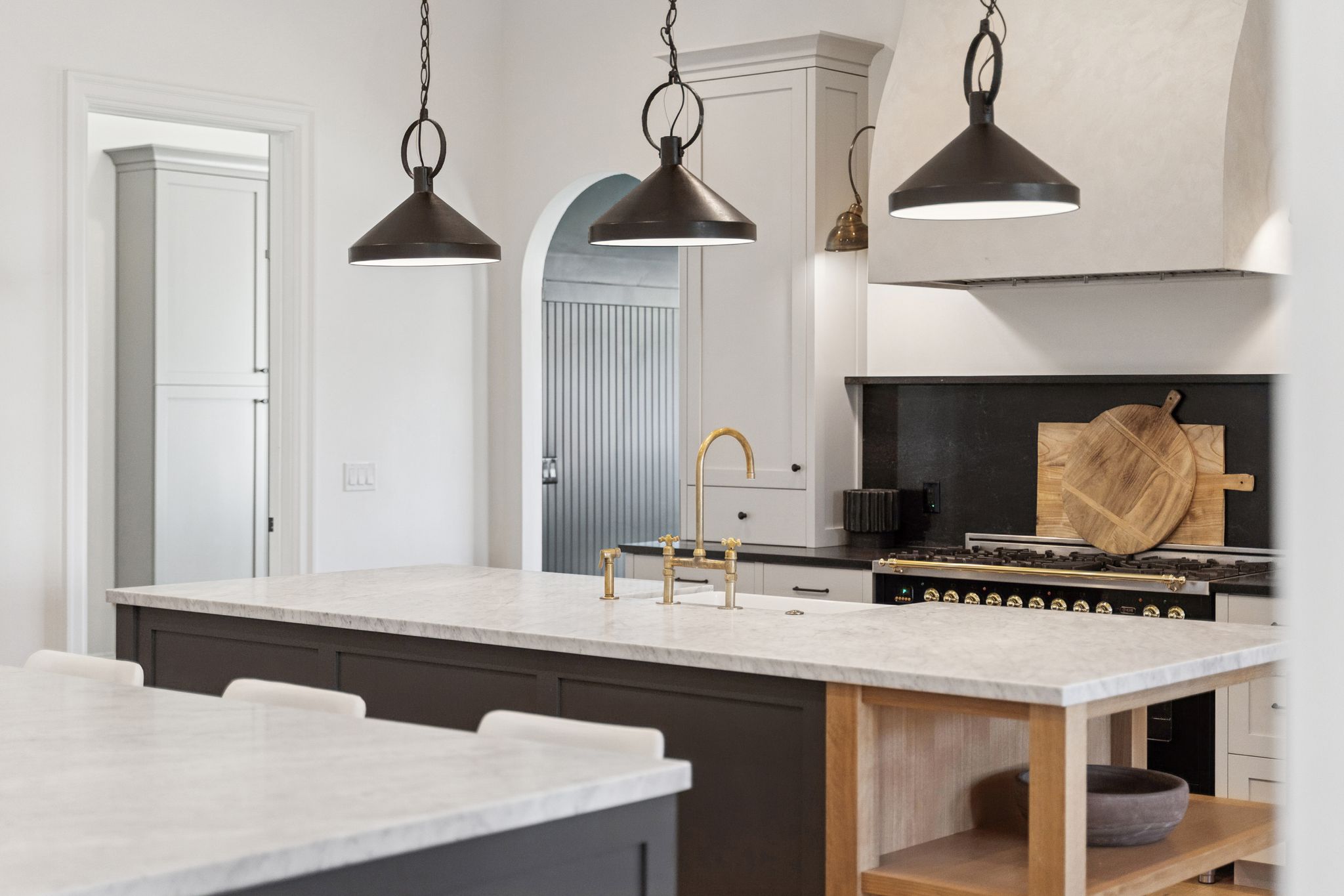 Kitchen with open shelves, dark stone counters, hanging light fixtures, and gas range oven