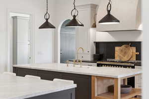 Kitchen with open shelves, dark stone counters, hanging light fixtures, and gas range oven