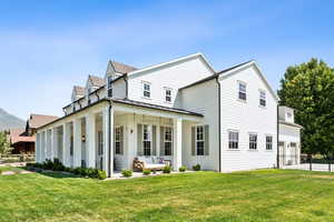 Rear view of property featuring a standing seam roof, an attached garage, a porch, a metal roof, and driveway