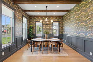 Dining area featuring wallpapered walls, a chandelier, light wood-style floors, healthy amount of natural light, and a decorative wall