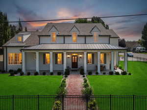 Modern inspired farmhouse featuring a fenced front yard, a porch, and a shingled roof