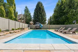 View of swimming pool featuring a water slide, a fenced backyard, and a patio area