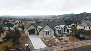View of front facade with stone siding, a residential view, driveway, and a garage