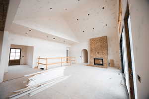 Unfurnished living room featuring a towering ceiling, arched walkways, and a large fireplace