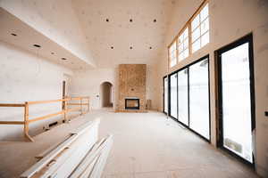 Unfurnished living room with arched walkways, a high ceiling, and a large fireplace