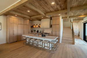 Kitchen with a breakfast bar, light wood finished floors, recessed lighting, a kitchen island with sink, and light brown cabinets