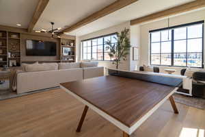 Dining room featuring beamed ceiling, light wood-style flooring, healthy amount of natural light, and built in shelves