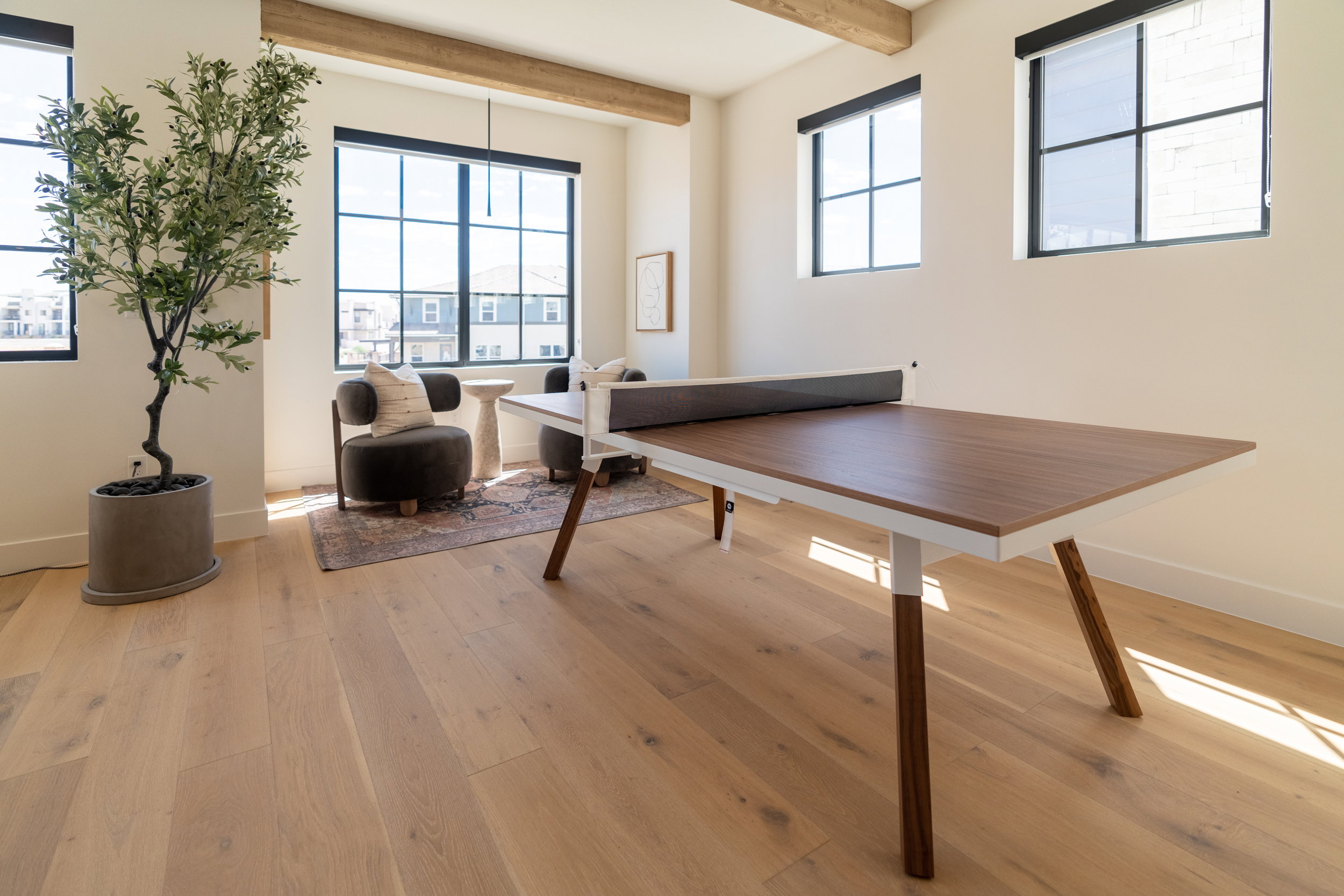 Recreation room featuring healthy amount of natural light, beamed ceiling, and light wood-style floors