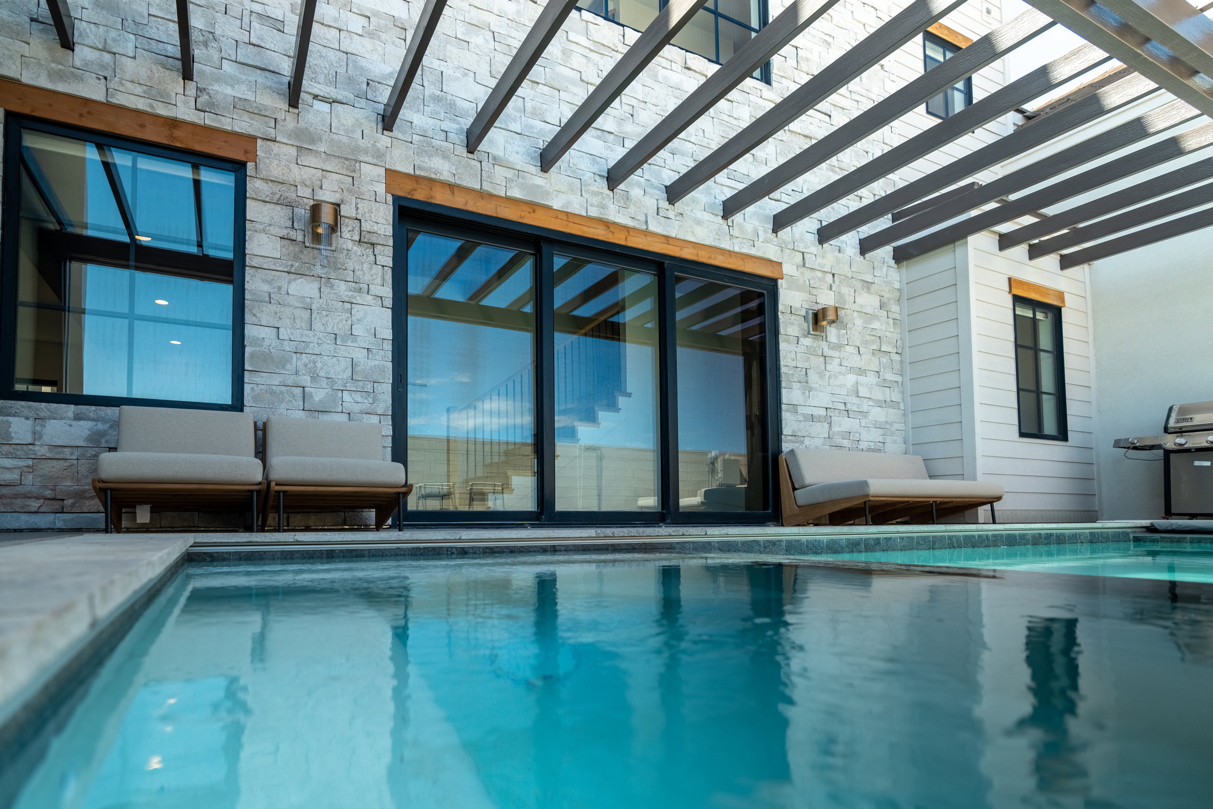 Indoor pool with a patio, area for grilling, and a pergola