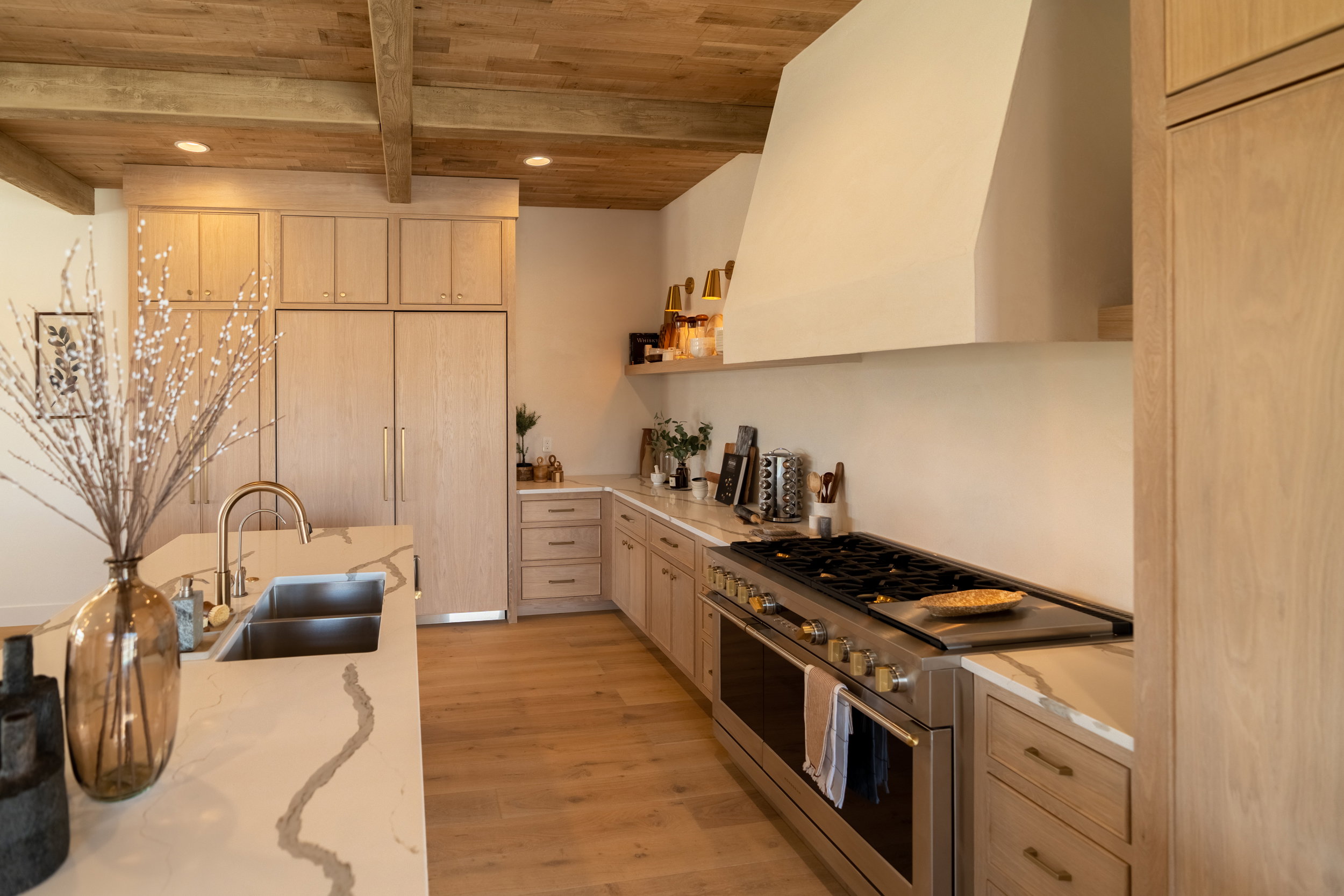 Kitchen featuring double oven range, premium range hood, open shelves, light stone counters, and light wood-type flooring