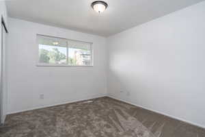 Empty room with dark colored carpet and baseboards