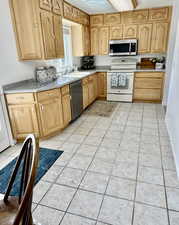 Kitchen featuring appliances with stainless steel finishes, light tile patterned floors, light countertops, and light brown cabinets