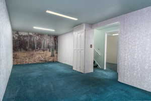 Finished basement featuring dark colored carpet and stairway