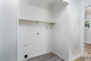 Washroom with light wood-style floors, hookup for a washing machine, and electric dryer hookup