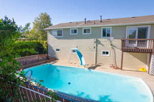 View of pool with a water slide, a deck, and a patio area