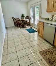 Kitchen featuring stainless steel dishwasher, light tile patterned floors, and light countertops