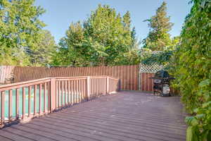 Deck with a pool, grilling area, and a fenced backyard