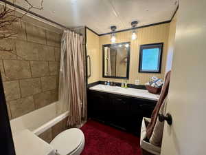 Bathroom featuring tiled shower / bath combo, crown molding, vanity, a textured ceiling, and wooden walls