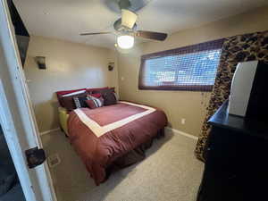Carpeted bedroom with a ceiling fan and baseboards