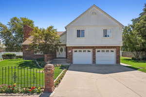 View of front of property featuring brick siding, concrete driveway, an attached garage, and stucco siding