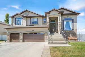 View of front of house with stone siding, stucco siding, an attached garage, and driveway