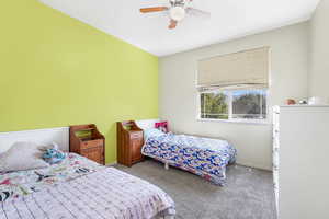 Carpeted bedroom featuring ceiling fan and baseboards