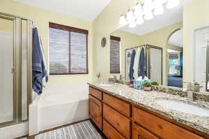 Ensuite bathroom with a stall shower, double vanity, and a garden tub