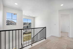 Hall with an upstairs landing, carpet floors, and recessed lighting