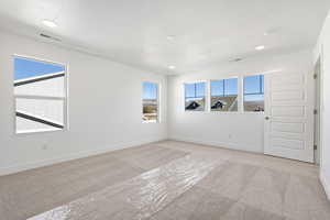 Unfurnished room with light colored carpet, recessed lighting, and a textured ceiling