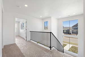 Hall featuring plenty of natural light, carpet floors, an upstairs landing, and recessed lighting
