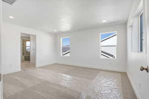 Unfurnished room featuring light colored carpet, healthy amount of natural light, recessed lighting, and a textured ceiling