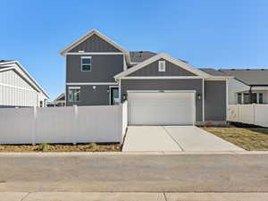 View of front of property with board and batten siding, driveway, a garage, and roof with shingles