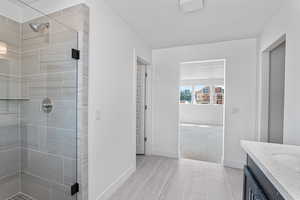 Full bath featuring vanity, a shower stall, and a textured ceiling