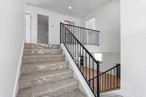 Staircase with baseboards and recessed lighting