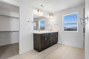 Full bath with double vanity, plenty of natural light, and a spacious closet