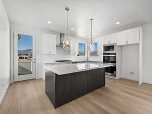 Kitchen featuring decorative backsplash, white cabinetry, a kitchen island, dark brown cabinets, and recessed lighting