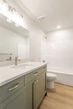 Bathroom featuring vanity, shower / washtub combination, light wood finished floors, and recessed lighting