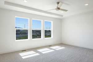 Unfurnished room featuring light carpet, a raised ceiling, recessed lighting, and a ceiling fan