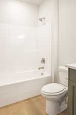 Bathroom with shower / washtub combination, vanity, and light wood-style floors