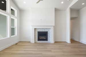 Unfurnished living room featuring recessed lighting, a fireplace, light wood-style floors, and a ceiling fan