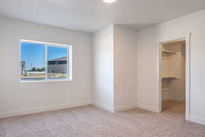 Unfurnished bedroom with light carpet and a spacious closet