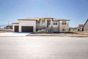 Prairie-style home with stone siding, an attached garage, driveway, and roof with shingles