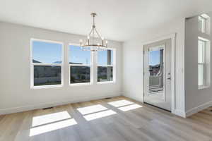 Unfurnished dining area with light wood-type flooring and a chandelier