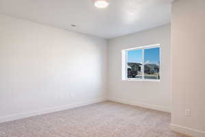 Unfurnished room featuring baseboards and light carpet