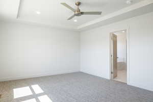Spare room with a tray ceiling, recessed lighting, light carpet, and ceiling fan