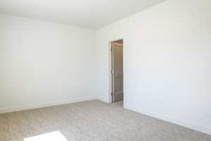 Empty room featuring baseboards and light colored carpet
